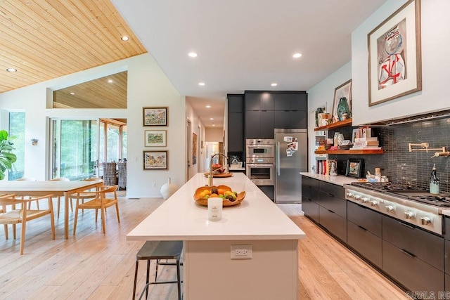 kitchen featuring appliances with stainless steel finishes, tasteful backsplash, a kitchen island, wooden ceiling, and a kitchen bar