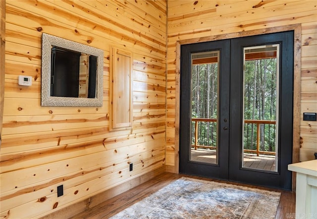 entryway with wood-type flooring, wooden walls, and french doors