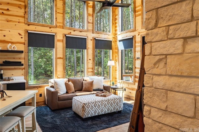 living room featuring a towering ceiling, hardwood / wood-style flooring, and wood walls