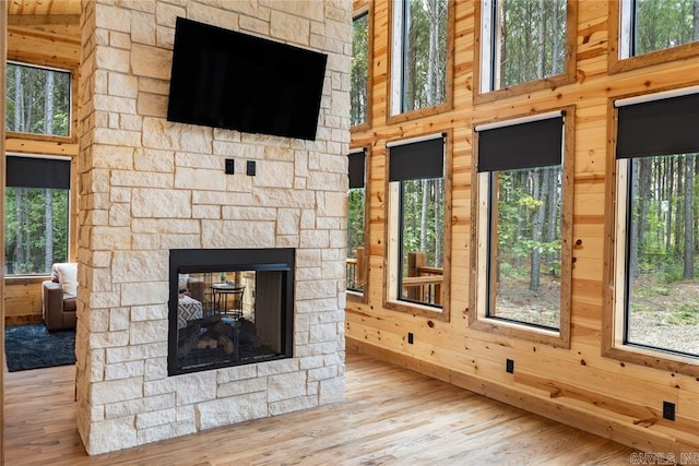 unfurnished living room featuring a fireplace, wood walls, and light hardwood / wood-style floors