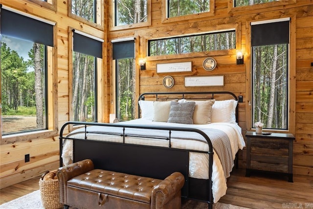 bedroom with a high ceiling, wood walls, and hardwood / wood-style flooring