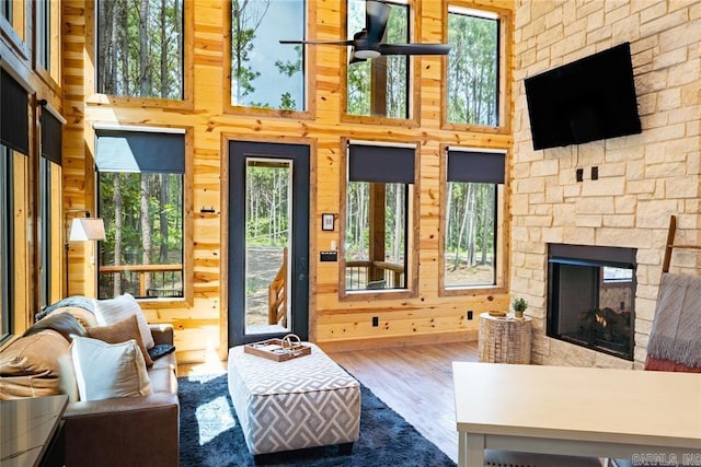 living room with ceiling fan, a stone fireplace, hardwood / wood-style floors, and a healthy amount of sunlight