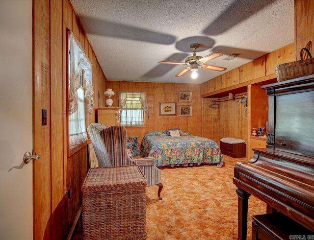 carpeted bedroom with a closet, wood walls, ceiling fan, and a textured ceiling