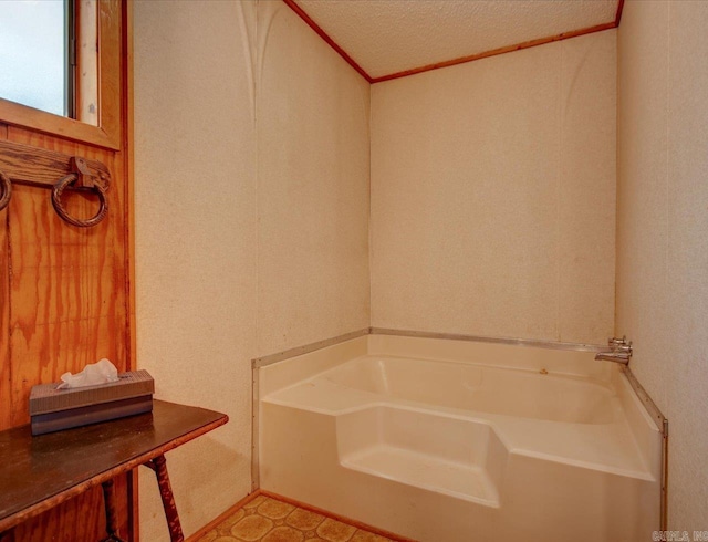 bathroom with ornamental molding, a textured ceiling, and a bath