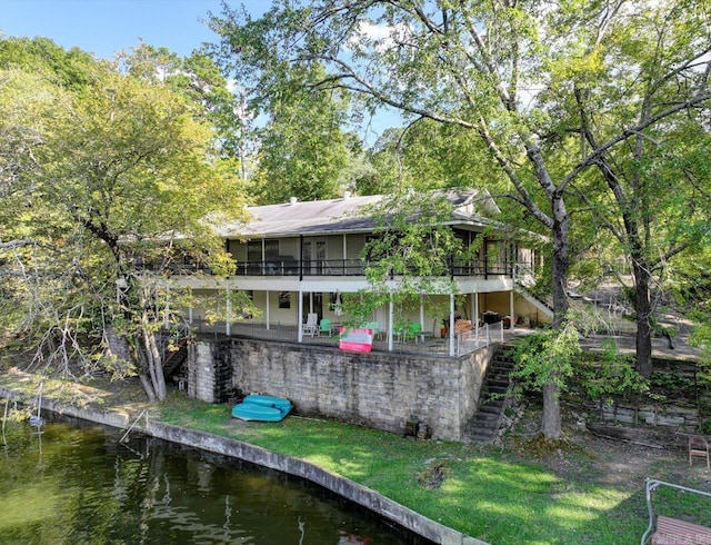 exterior space featuring a lawn and a deck with water view