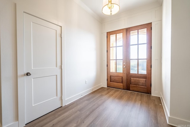 doorway featuring ornamental molding, french doors, and light wood-type flooring