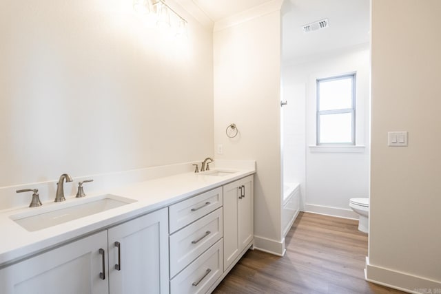 bathroom with vanity, toilet, ornamental molding, and hardwood / wood-style floors