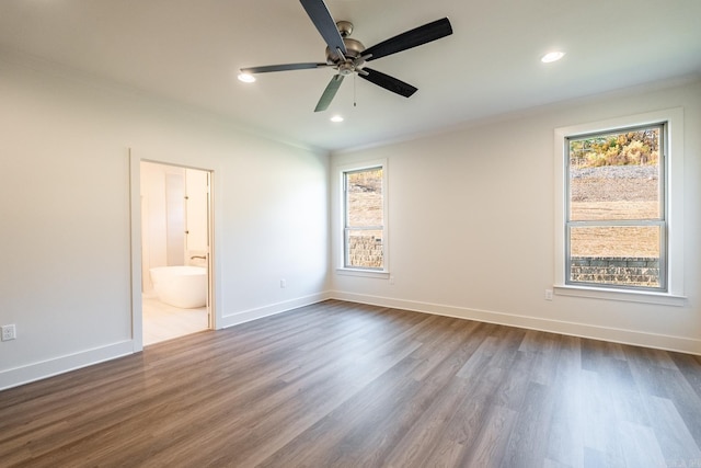 unfurnished bedroom with dark hardwood / wood-style flooring, multiple windows, ensuite bathroom, and ceiling fan