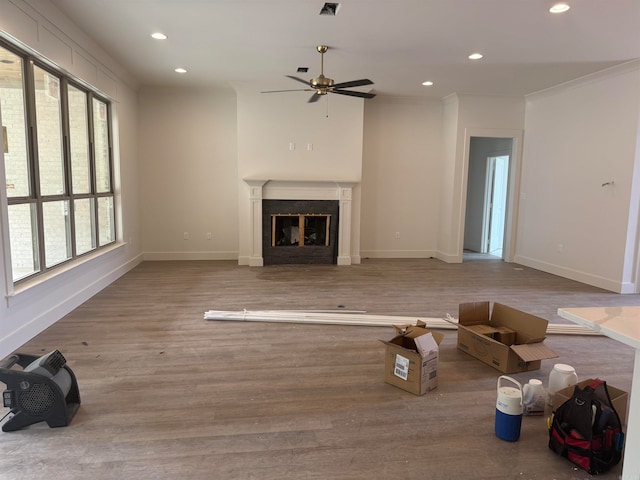 unfurnished living room with ceiling fan, ornamental molding, and hardwood / wood-style floors