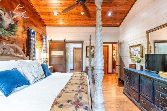 bedroom featuring ceiling fan, light hardwood / wood-style flooring, a barn door, wooden ceiling, and vaulted ceiling