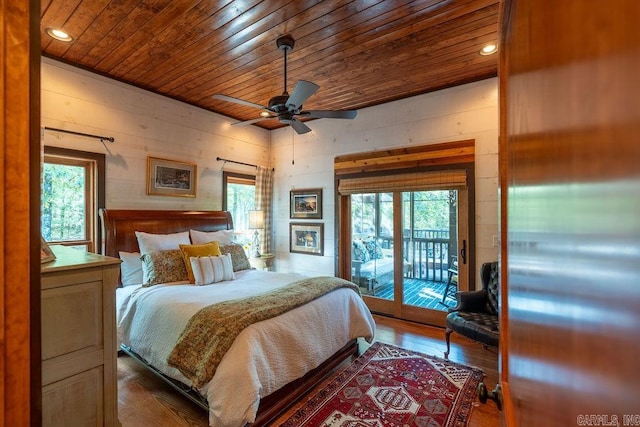 bedroom featuring wooden walls, multiple windows, access to exterior, and dark hardwood / wood-style flooring