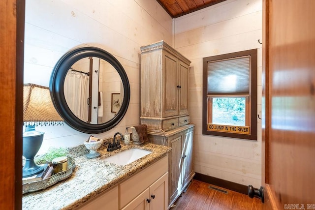 bathroom featuring wooden ceiling, wooden walls, vanity, and hardwood / wood-style floors