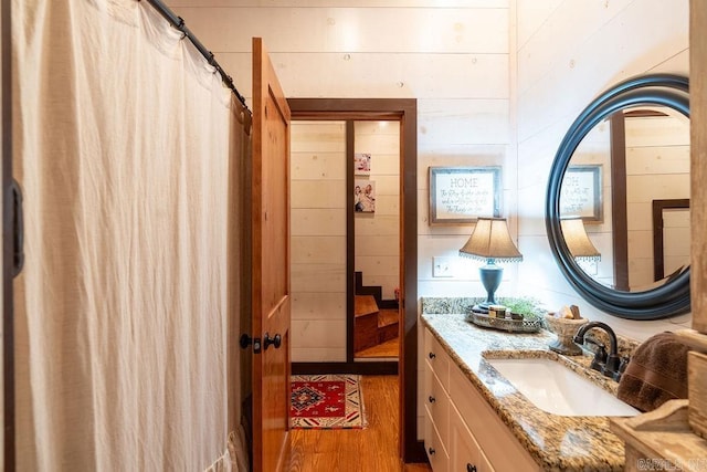 bathroom with wooden walls, hardwood / wood-style flooring, and vanity