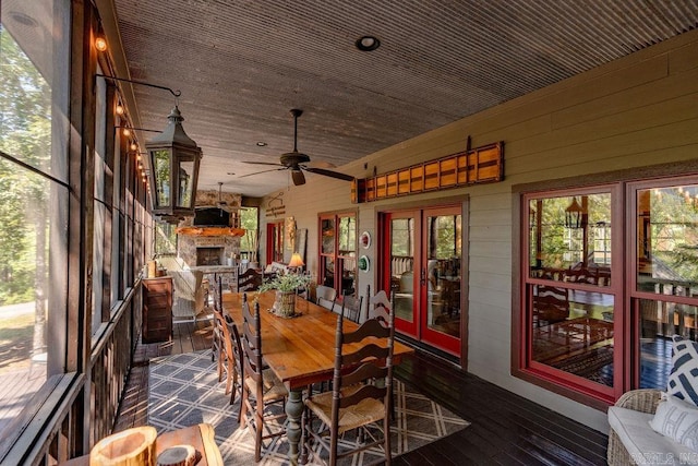 sunroom / solarium featuring a stone fireplace and ceiling fan