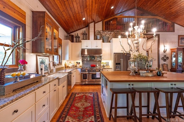 kitchen with white cabinets, high end appliances, wooden ceiling, a notable chandelier, and wood counters