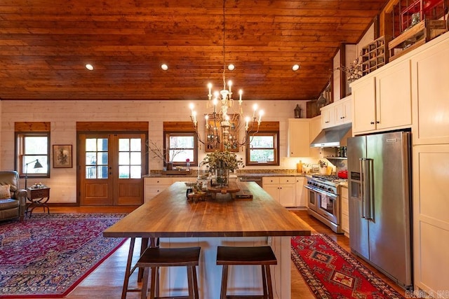 kitchen featuring a healthy amount of sunlight, a kitchen island, wood counters, and high quality appliances