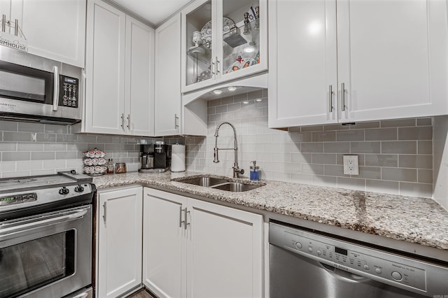 kitchen featuring white cabinets, stainless steel appliances, backsplash, and sink