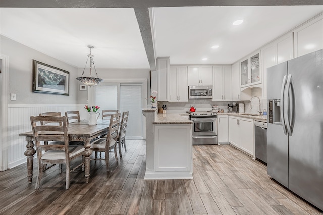 kitchen featuring appliances with stainless steel finishes, hardwood / wood-style flooring, pendant lighting, and white cabinets