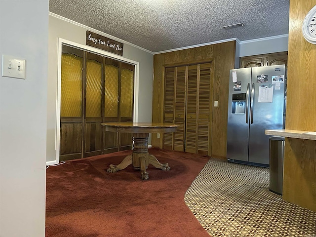 dining area with a textured ceiling, ornamental molding, and carpet