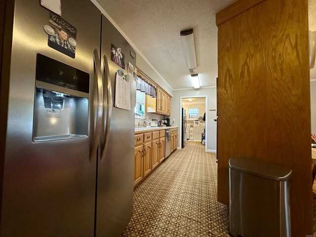 kitchen featuring a textured ceiling, stainless steel appliances, sink, and ornamental molding