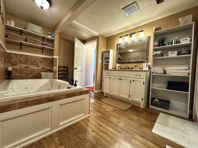 bathroom featuring vanity, a textured ceiling, hardwood / wood-style flooring, and a washtub