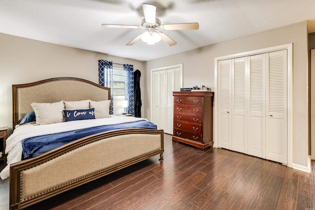 bedroom featuring ceiling fan, a textured ceiling, two closets, and dark wood-type flooring