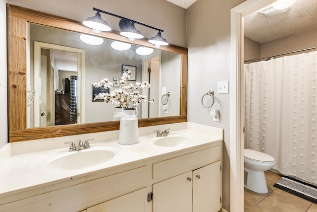 bathroom featuring tile patterned flooring, a textured ceiling, toilet, vanity, and curtained shower