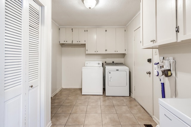 clothes washing area featuring a textured ceiling, crown molding, washing machine and dryer, and cabinets