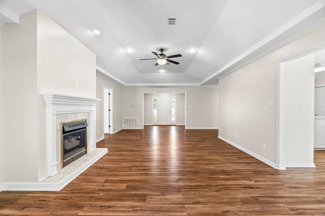 unfurnished living room featuring a tile fireplace, dark wood-type flooring, a raised ceiling, ornamental molding, and ceiling fan