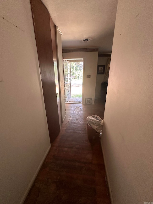 corridor with a textured ceiling and dark hardwood / wood-style flooring