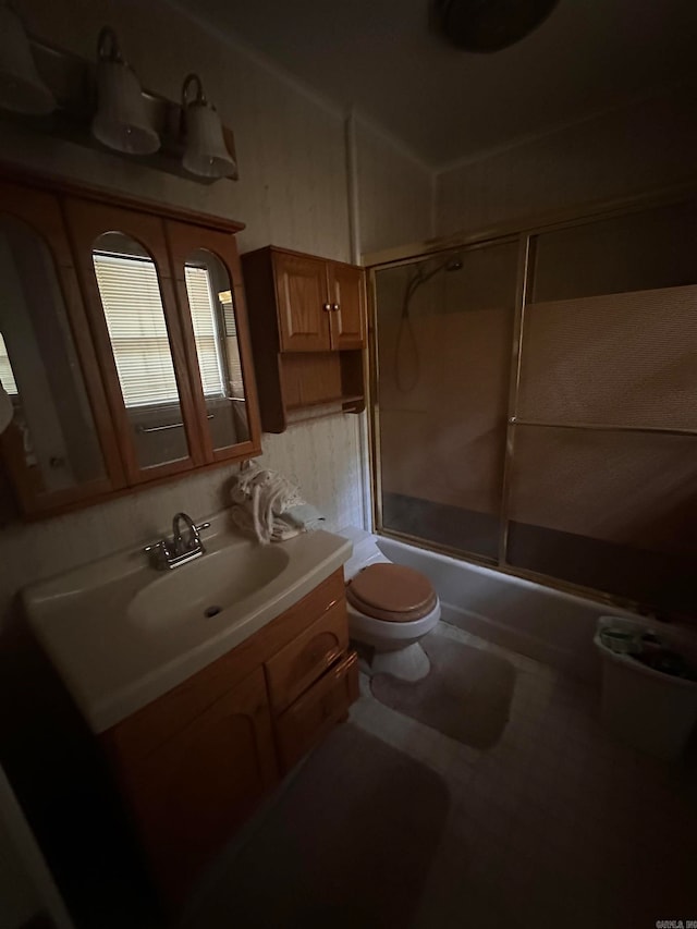 full bathroom featuring toilet, vanity, and bath / shower combo with glass door