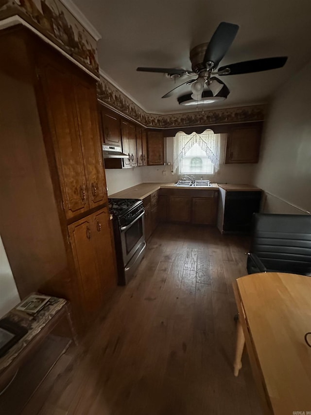 kitchen with stainless steel gas stove, ceiling fan, dark hardwood / wood-style floors, and sink