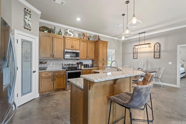 kitchen featuring a kitchen island with sink, a kitchen breakfast bar, appliances with stainless steel finishes, concrete floors, and decorative light fixtures