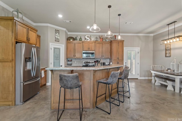 kitchen with stainless steel appliances, decorative light fixtures, a breakfast bar area, a center island with sink, and ornamental molding