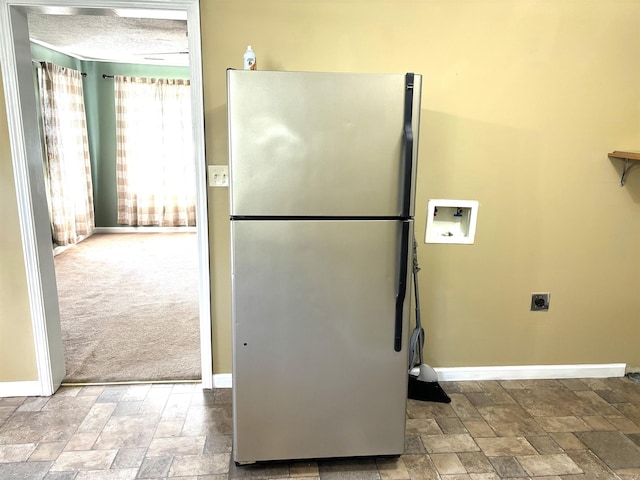 kitchen featuring a textured ceiling, light colored carpet, and stainless steel refrigerator