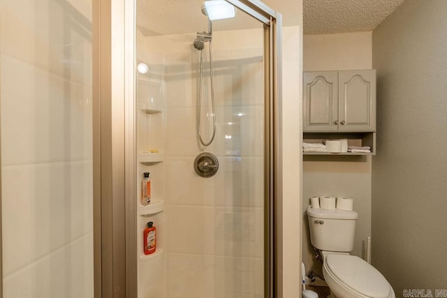 bathroom featuring a textured ceiling, a shower with door, and toilet