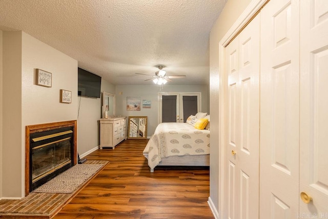 bedroom with ceiling fan, dark wood-type flooring, and a textured ceiling