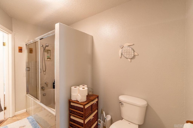 bathroom featuring bath / shower combo with glass door, a textured ceiling, toilet, and tile patterned floors