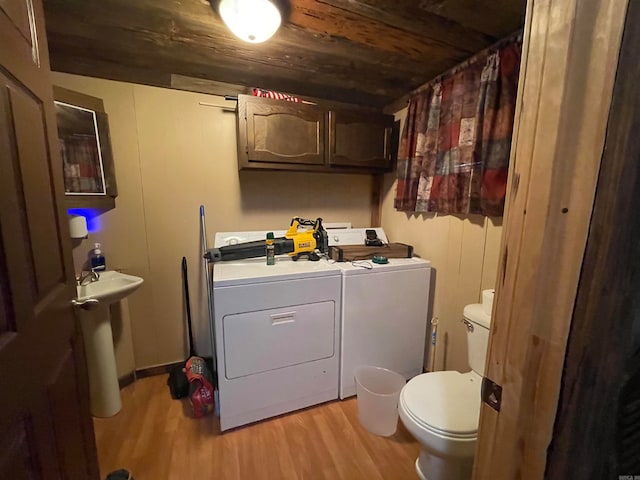 washroom featuring sink, light hardwood / wood-style floors, washer and dryer, and wood ceiling