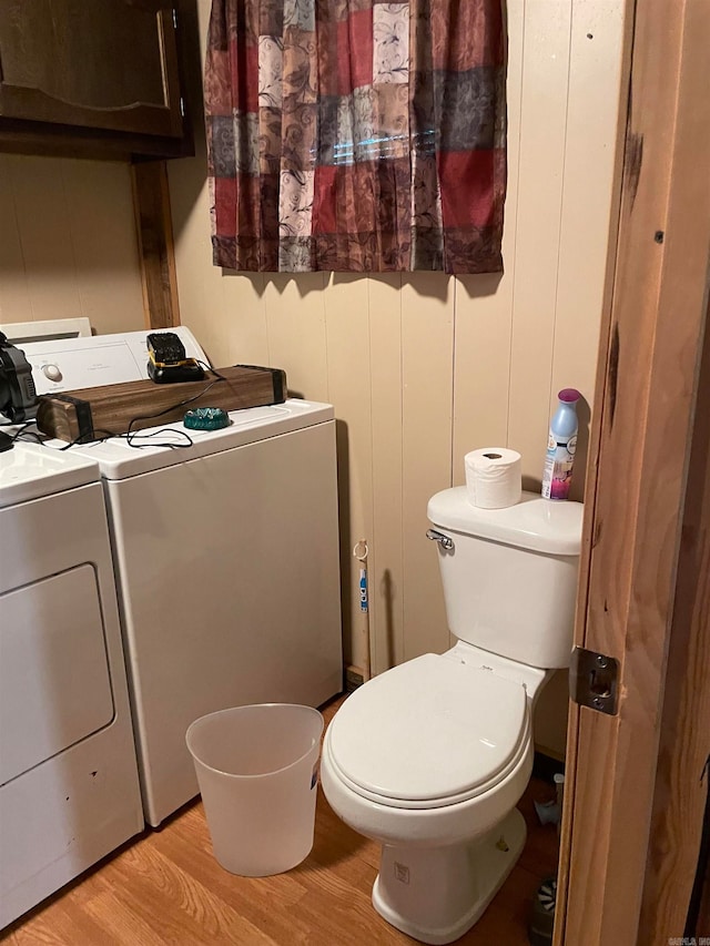 bathroom with wood-type flooring, washer and dryer, and toilet