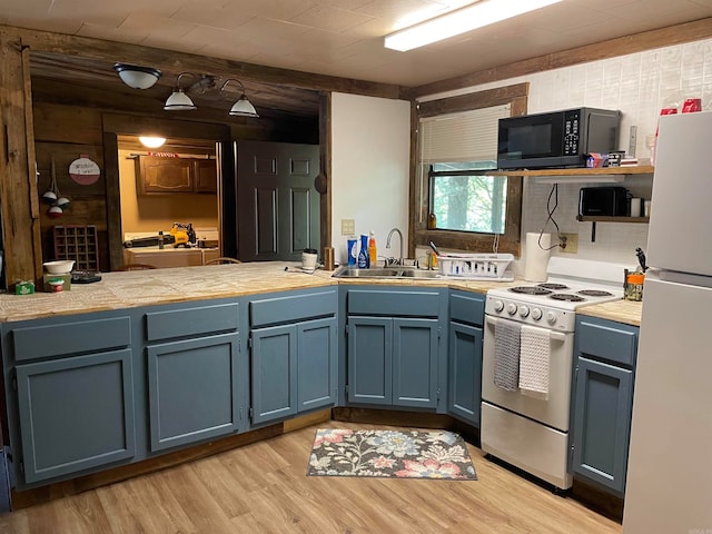 kitchen featuring stove, sink, white fridge, blue cabinetry, and light hardwood / wood-style floors