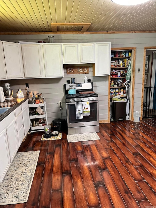 kitchen featuring wood walls, white cabinetry, stainless steel stove, dark hardwood / wood-style floors, and wooden ceiling