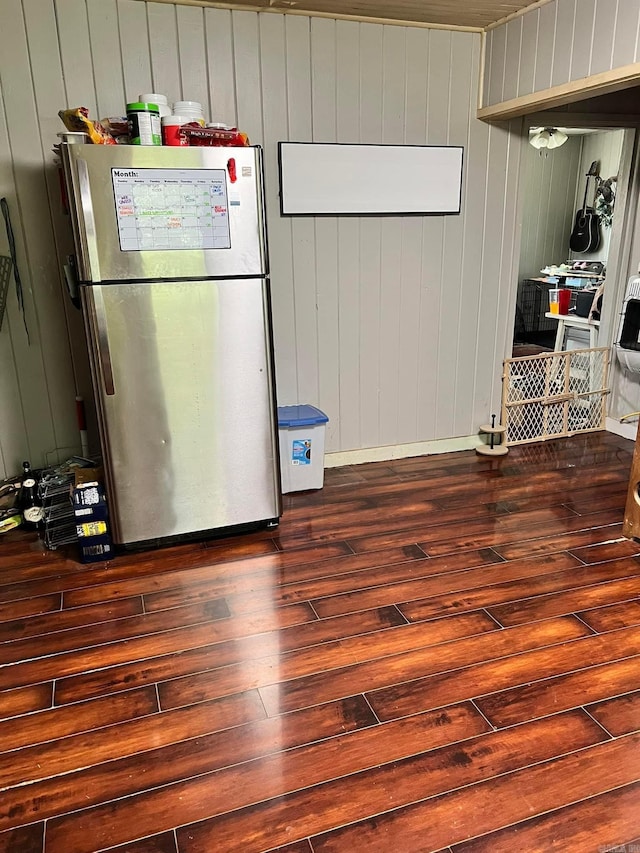 kitchen featuring wood walls, dark hardwood / wood-style floors, and stainless steel refrigerator