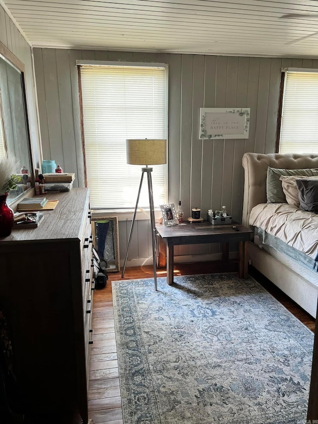 bedroom featuring multiple windows, wood-type flooring, wooden walls, and wooden ceiling