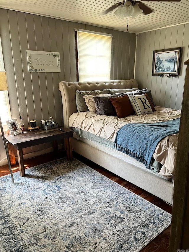 bedroom with ceiling fan, wooden walls, wood ceiling, and dark hardwood / wood-style floors