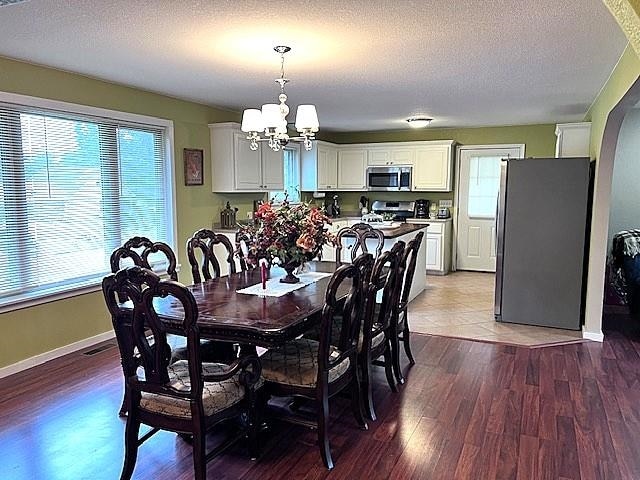 dining area with a chandelier, a textured ceiling, and hardwood / wood-style floors