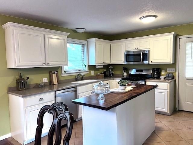 kitchen featuring sink, wooden counters, white cabinetry, appliances with stainless steel finishes, and a center island