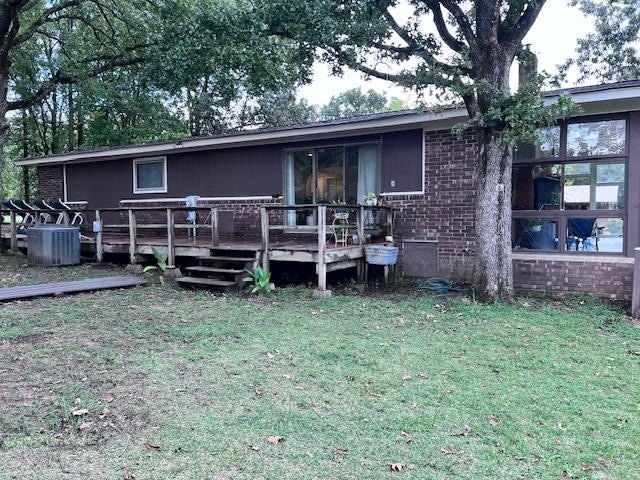 back of house featuring central AC unit, a deck, and a lawn