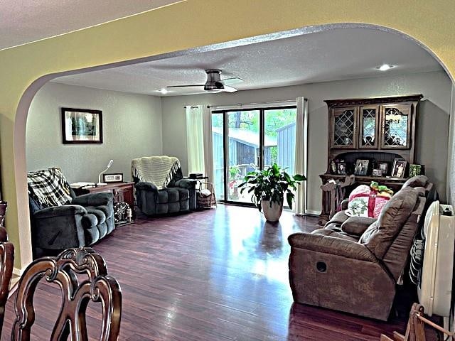 living room featuring a textured ceiling, ceiling fan, and dark hardwood / wood-style flooring