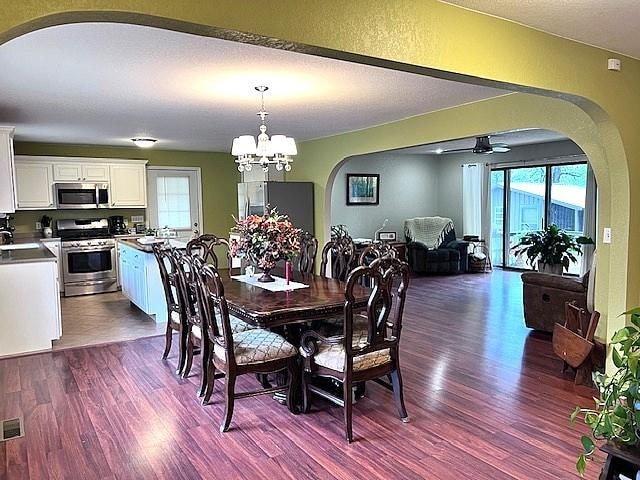 dining area with sink, ceiling fan with notable chandelier, and hardwood / wood-style floors